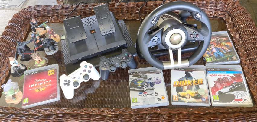 Play station 3 with controllers, driving wheel, and games.
